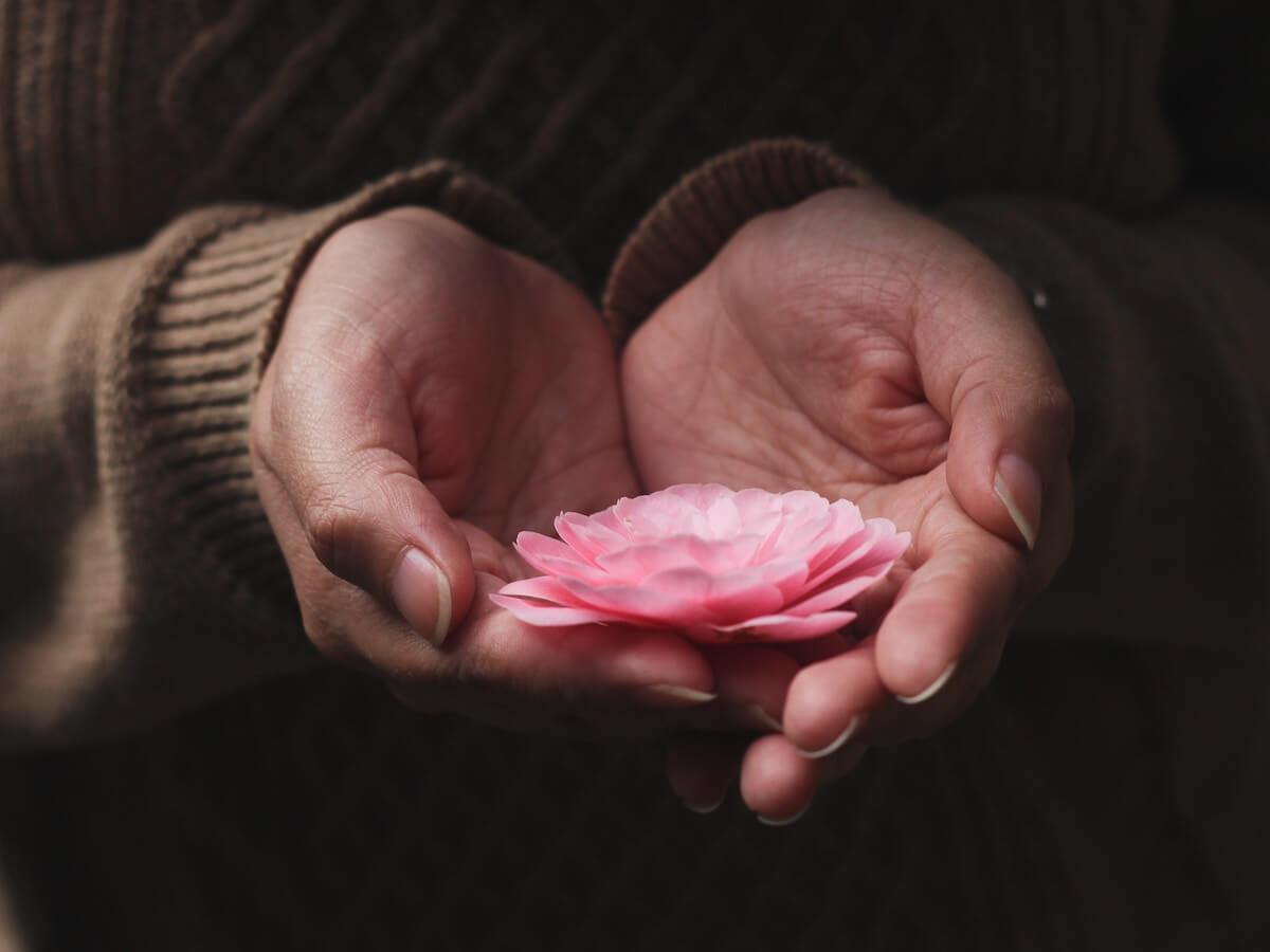 Hands holding a flower in remembrance